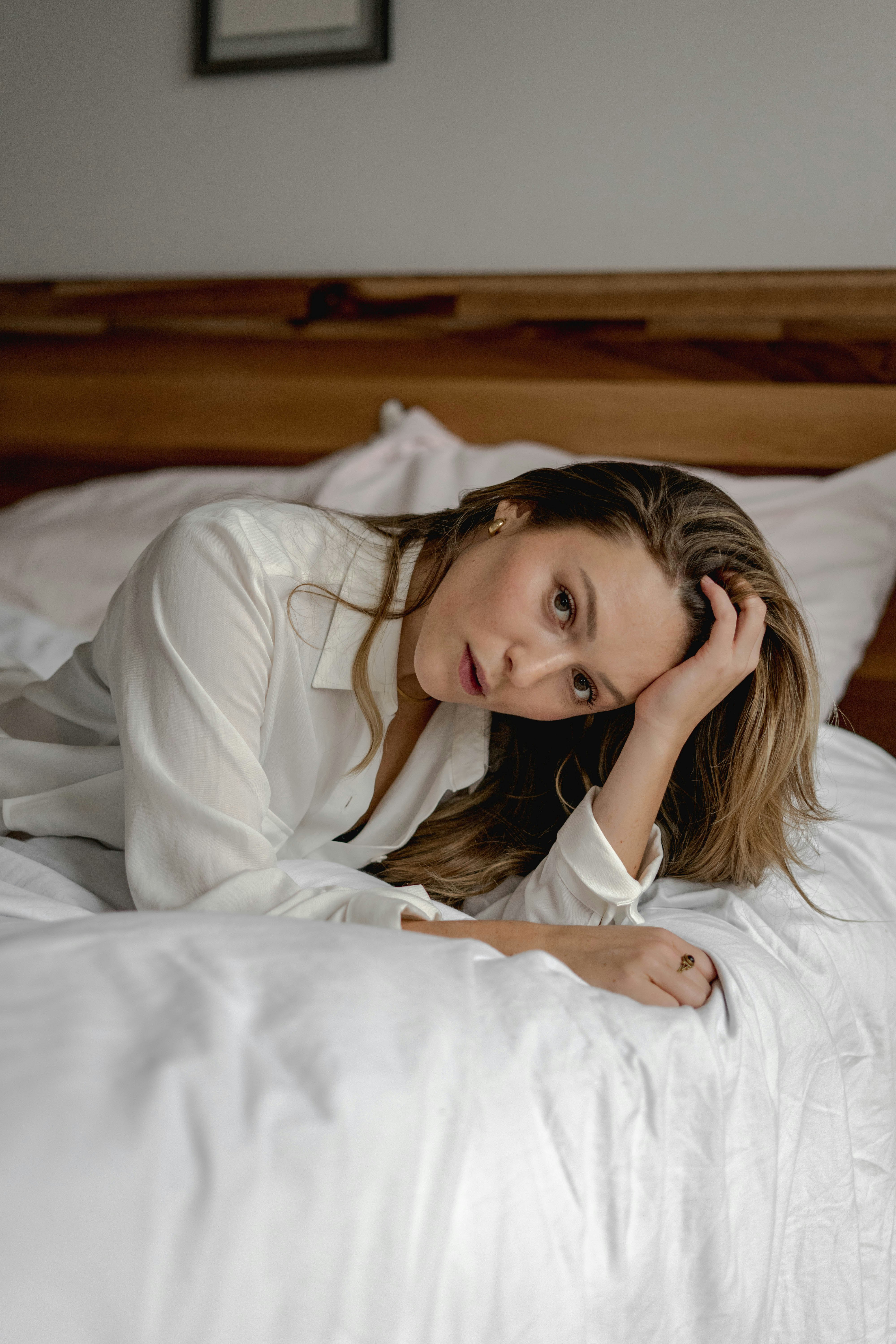 woman in white long sleeve shirt lying on bed